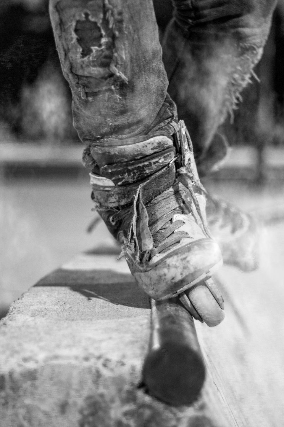 Cloud pattern style close-up of a heavily worn inline skate performing a rail grind, with distressed clothing and scuffed skate boots emphasizing street skating action and durability.